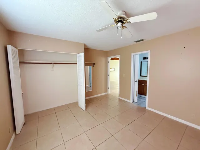 an empty room with closet and a ceiling fan