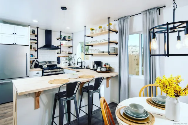 a kitchen with stainless steel appliances a white table chairs and a refrigerator