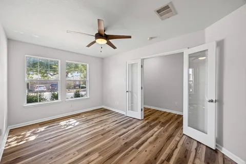 a view of empty room with wooden floor and fan