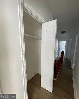 a walk in closet with wooden floor