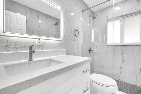 a bathroom with a sink a toilet and a large mirror