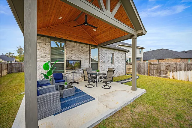 a view of a patio with couches table and chairs under an umbrella