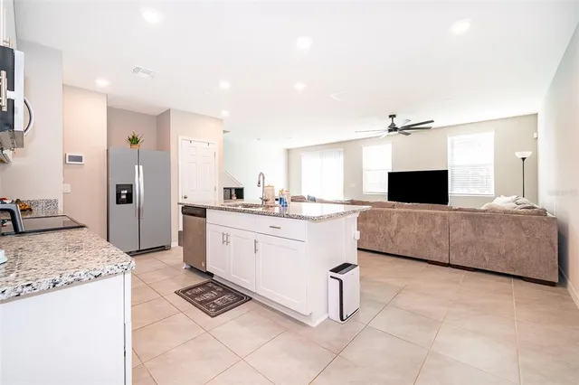a large kitchen with kitchen island granite countertop a sink and white cabinets
