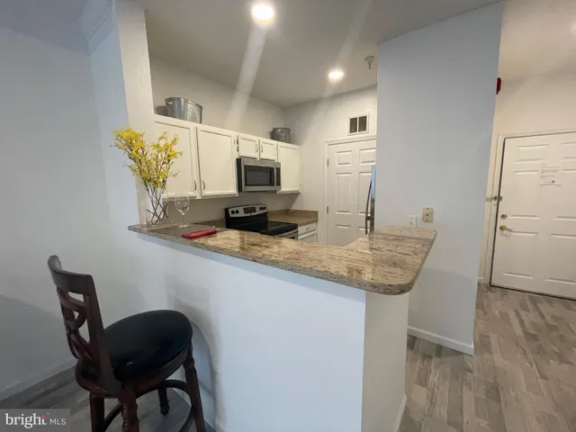 a kitchen with kitchen island a dining table chairs stainless steel appliances and cabinets