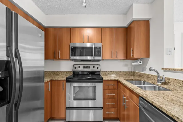 a kitchen with stainless steel appliances granite countertop a sink a stove microwave and refrigerator