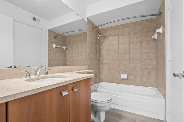 a bathroom with a granite countertop sink a toilet a mirror a bathtub and shower