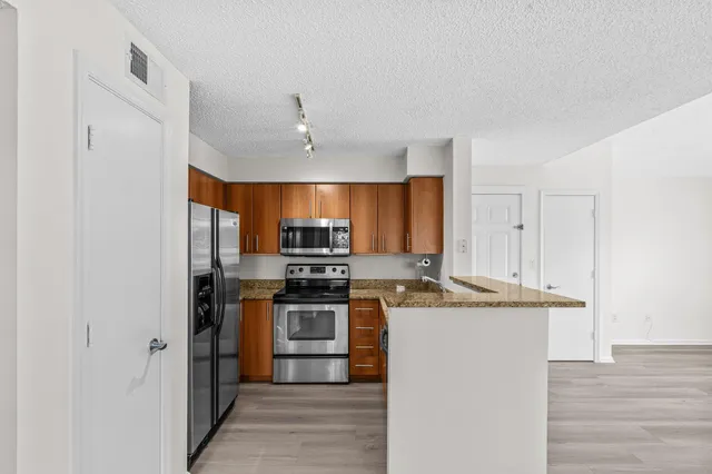 a kitchen with stainless steel appliances granite countertop a stove top oven a sink and a refrigerator