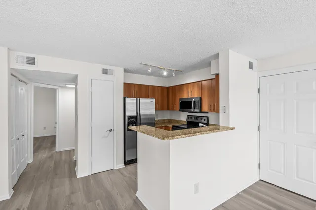 a kitchen with stainless steel appliances a stove top oven a sink and a refrigerator