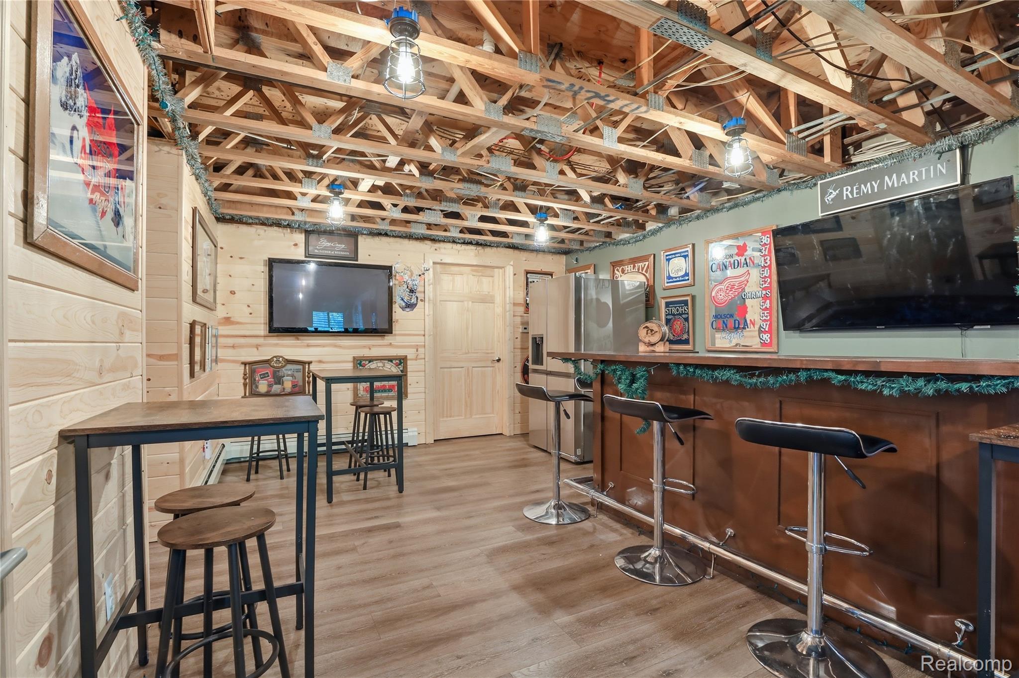 14830 Sheridan Road Byron, MI 48418 - Photo 38 of 74 Entertainment space featuring a built-in bar with wood-finish paneling, an exposed wood beam ceiling, plank flooring, and shiplap wall finishes