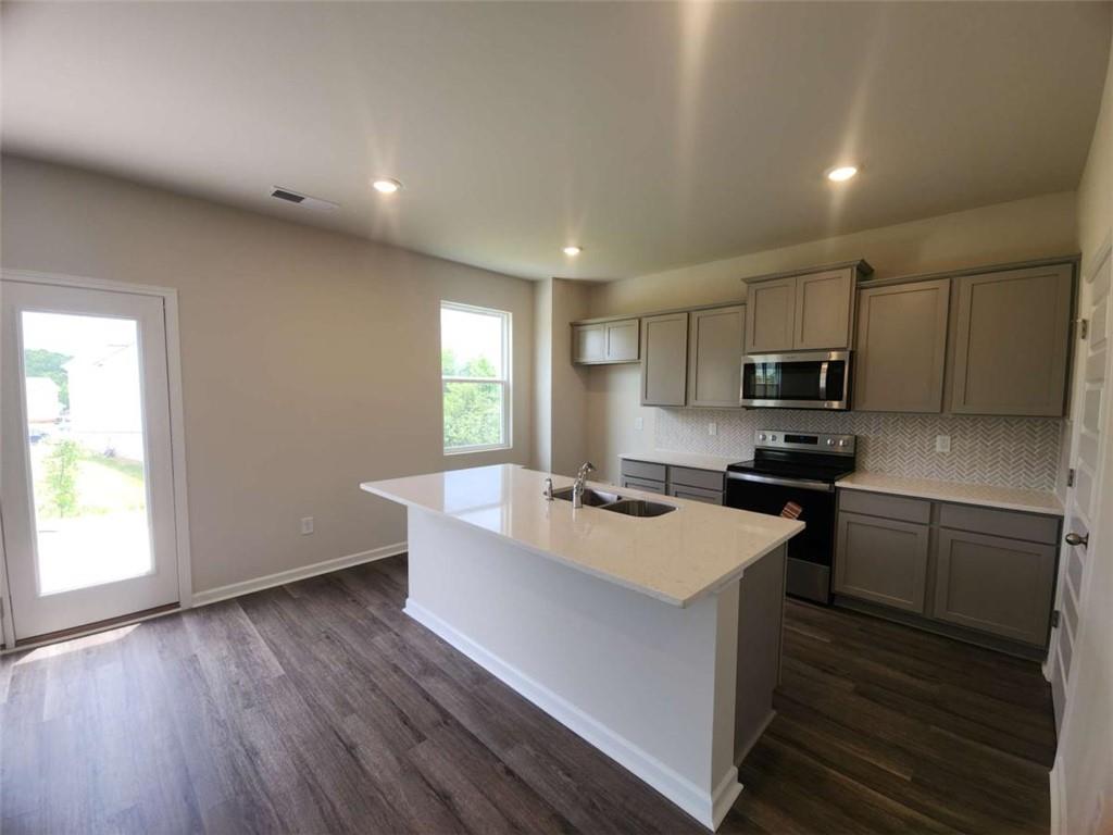146 Aster Avenue Locust Grove, GA 30248 - Photo 4 of 28 a kitchen with stainless steel appliances granite countertop a sink a stove a refrigerator and cabinets