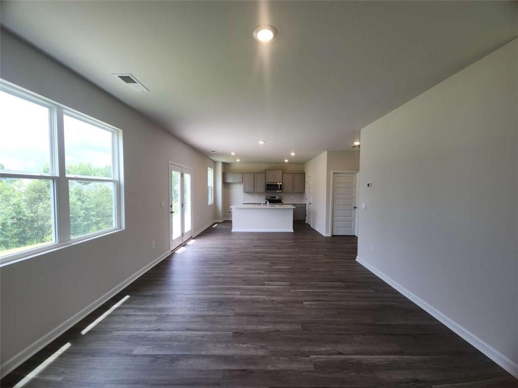 146 Aster Avenue Locust Grove, GA 30248 - Photo 8 of 28 a view of an empty room and kitchen with wooden floor