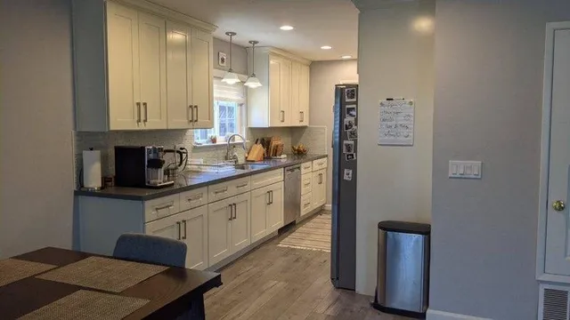 a kitchen with stainless steel appliances granite countertop a refrigerator a sink a stove and white cabinets