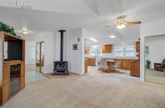 12825 Garrett Road Peyton, CO 80831 - Photo 12 of 47 Living room with ceiling fan, light colored carpet, and a wood stove
