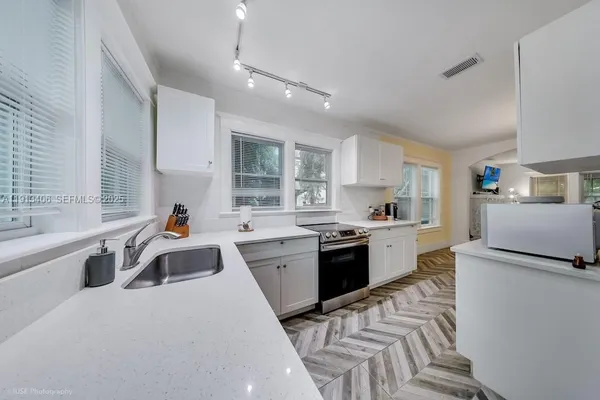 a large kitchen with stainless steel appliances granite countertop a sink dishwasher a stove and a refrigerator with wooden floor