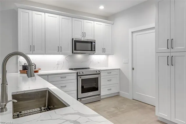a kitchen with granite countertop a stove top oven microwave and cabinets