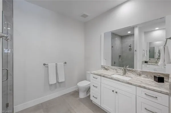 a bathroom with a granite countertop sink a toilet and a mirror