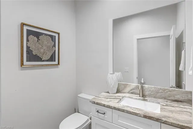 a bathroom with a granite countertop toilet and a sink