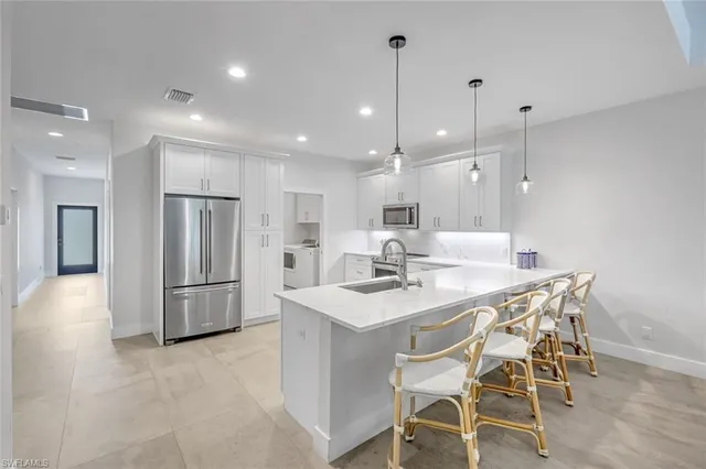 a kitchen with stainless steel appliances kitchen island granite countertop a table chairs sink and microwave