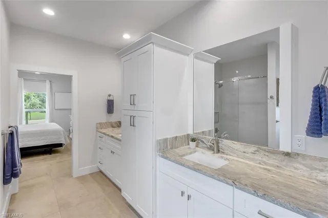 a en suite bathroom with a granite countertop sink and a mirror