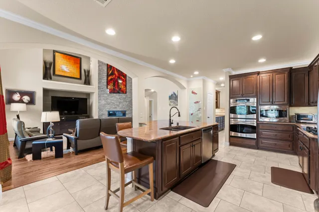 a kitchen with stainless steel appliances kitchen island granite countertop a stove a sink a dining table and chairs