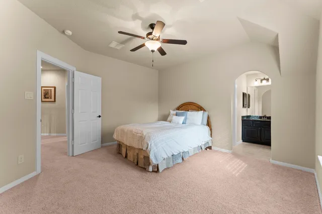 a spacious bedroom with a bed and a ceiling fan