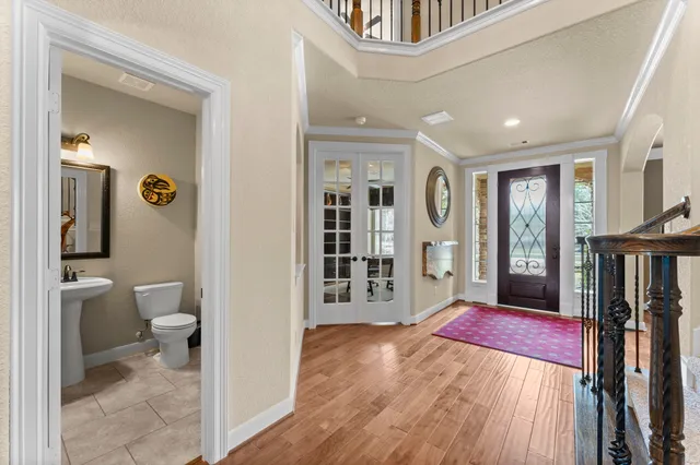 a view of a hallway with wooden floor and a bathroom