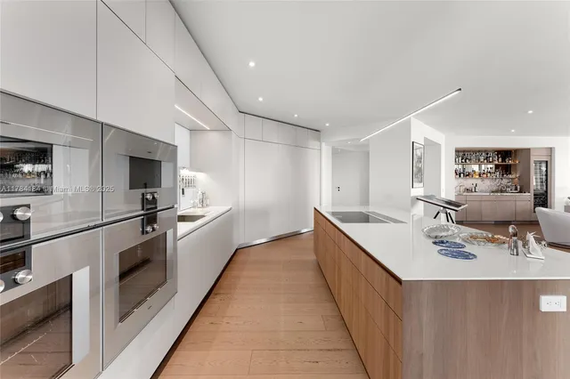 a large white kitchen with stainless steel appliances lots of counter space and a sink