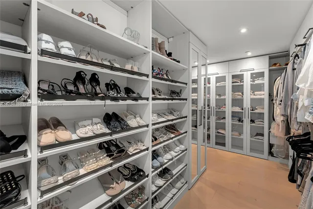 a view of walk in closet with clothes and shoes