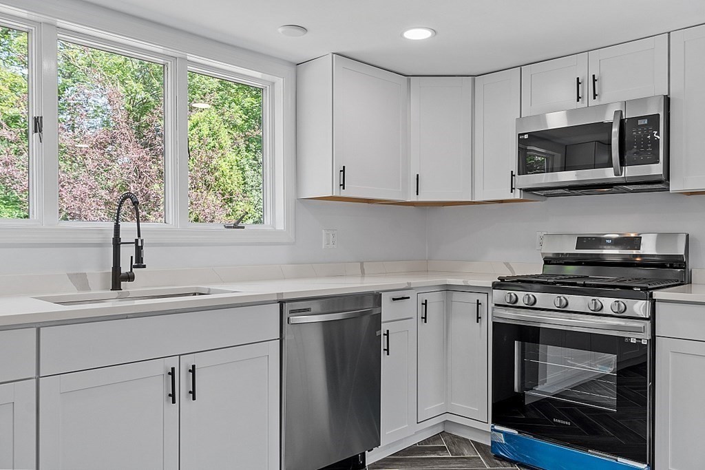 197 Beaman Road Sterling, MA 01564 - Photo 8 of 39 a kitchen with white cabinets appliances and a window