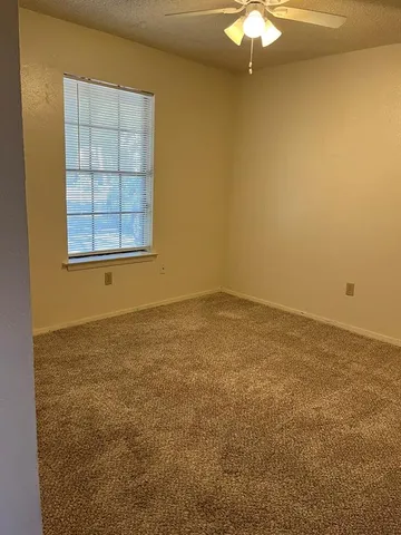 an empty room with a chandelier fan and window