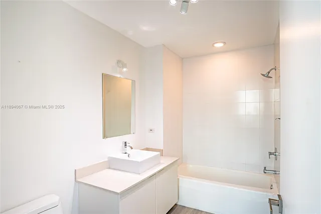 a bathroom with a bathtub sink vanity and mirror