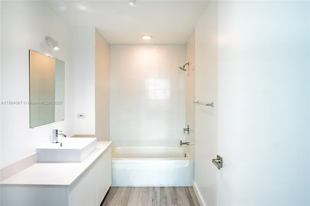 a bathroom with a tub sink shower and a mirror