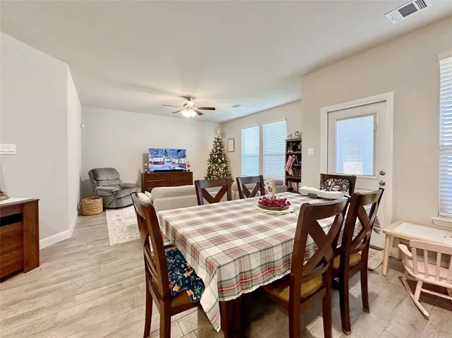 a view of a dining room and livingroom with furniture wooden floor a rug a painting and a chandelier