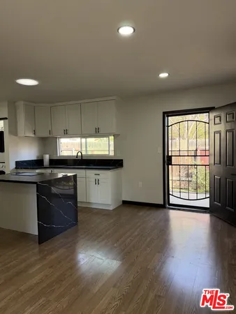 an open kitchen with granite countertop a stove top oven a sink and a microwave