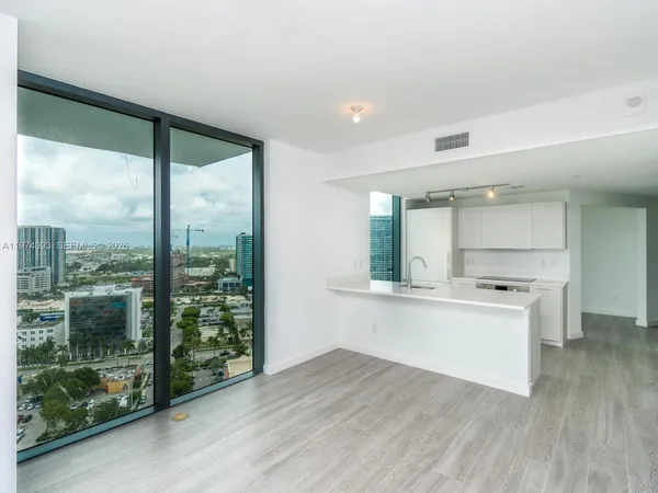 a kitchen with stainless steel appliances wooden floor and a large window