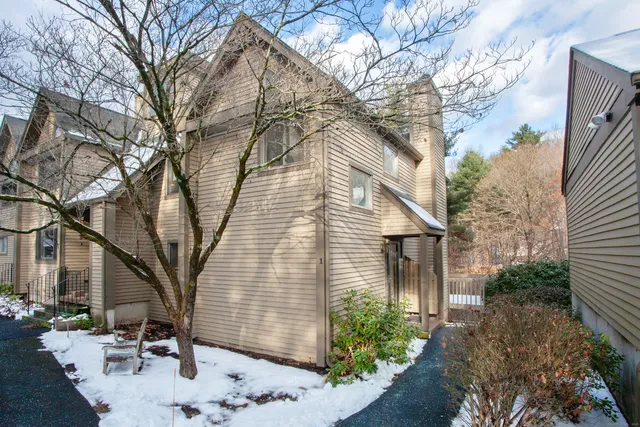 a backyard of a house with large tree and wooden fence