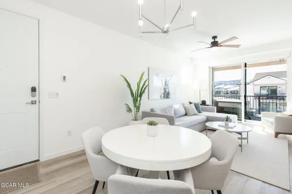 a kitchen with stainless steel appliances granite countertop a refrigerator a stove a sink dishwasher a dining table and chairs with wooden floor