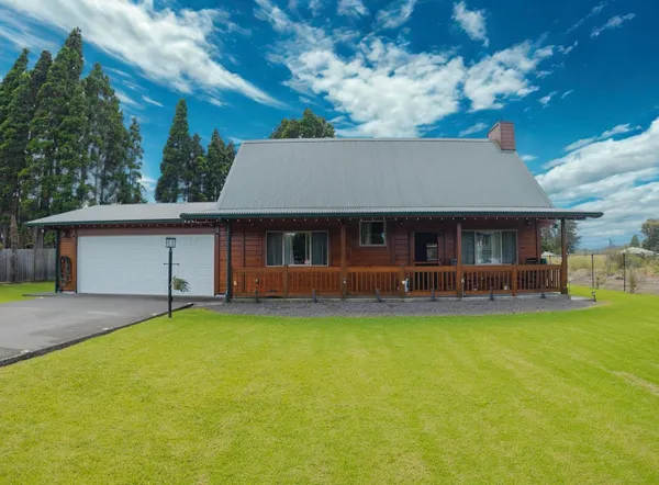 a front view of a house with a garden and tree