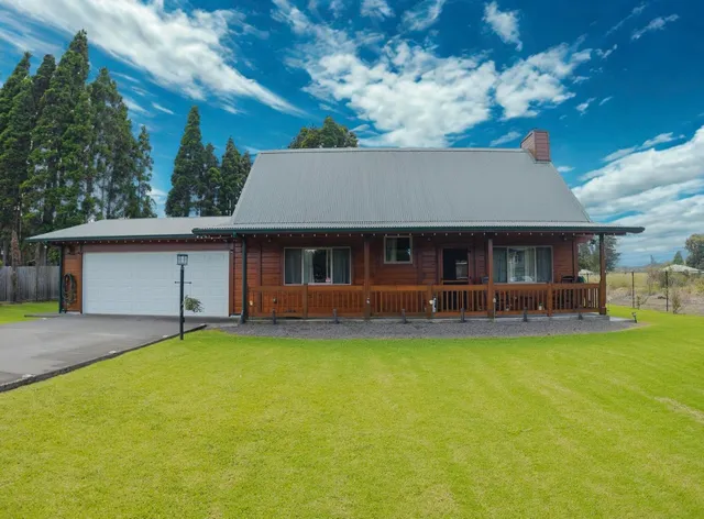 a front view of a house with a garden and tree