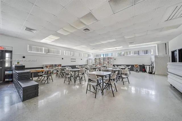 a dining hall with stainless steel appliances lots of white furniture a dining table and chairs