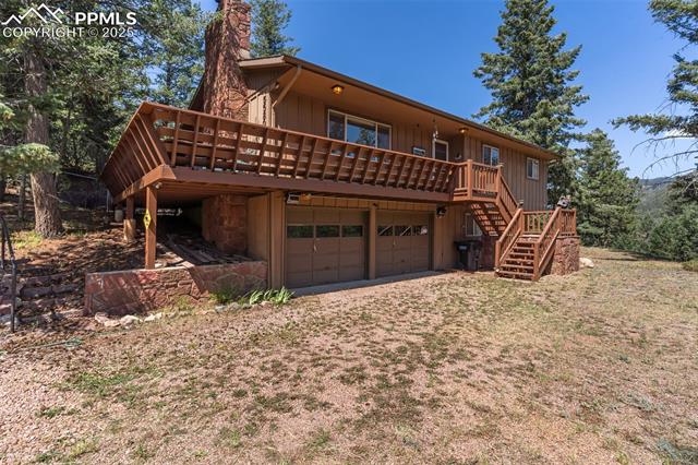 5580 Moosa Road Cascade, CO 80809 - Photo 33 of 35 Back of property with board and batten siding, stairs, a deck, a garage, and a chimney