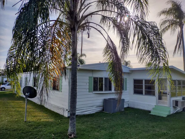 a view of a house with a yard and palm trees