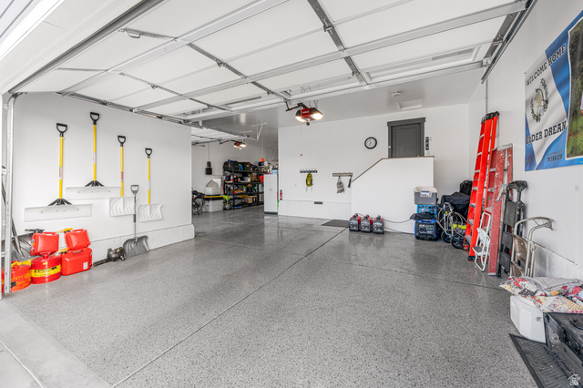 313 Old Maple Road South Weber, UT 84405 - Photo 34 of 35 Spacious garage featuring a durable epoxy floor, white painted walls, and an overhead garage door