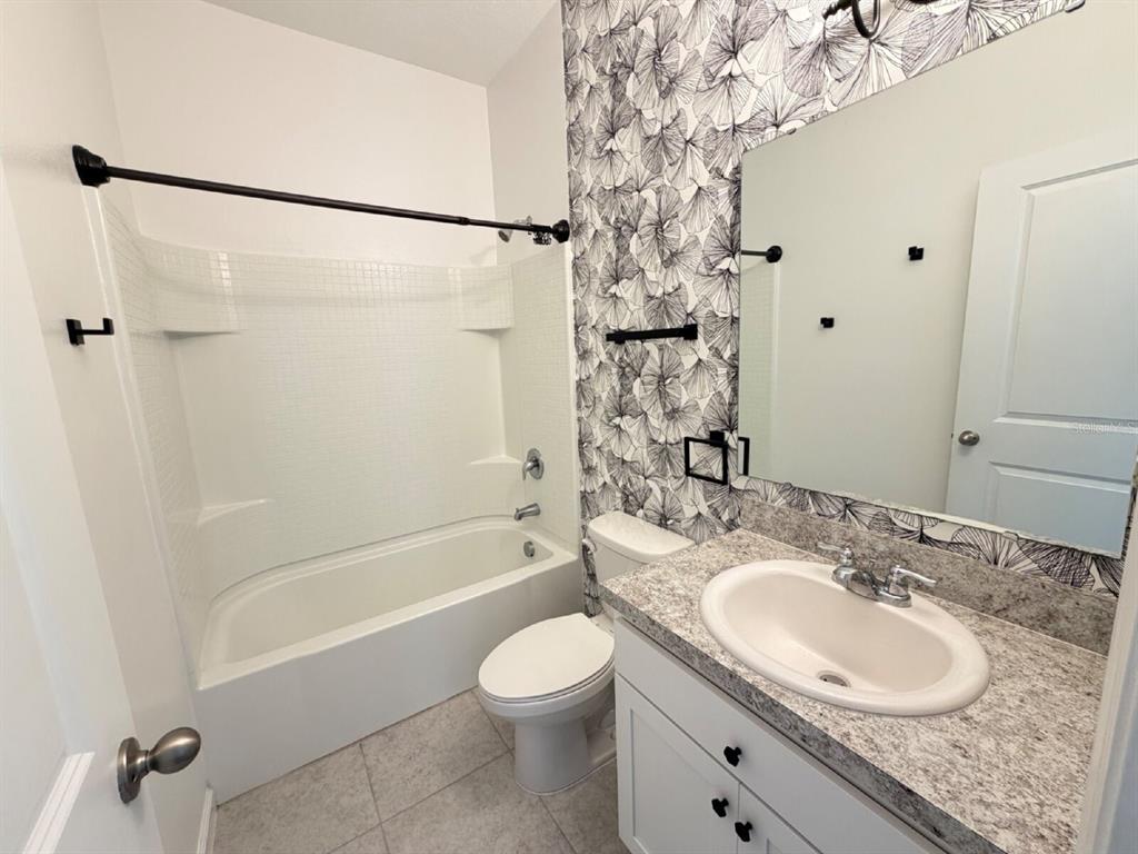 2021 Hemingway Circle Groveland, FL 34736 - Photo 10 of 18 a bathroom with a granite countertop sink toilet a shower and a mirror