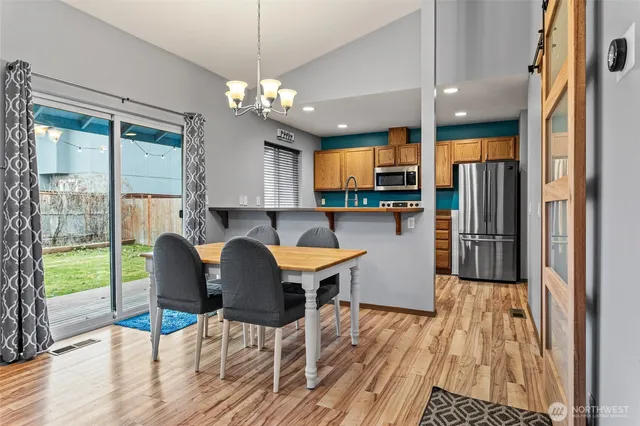 a kitchen with stainless steel appliances granite countertop table chairs and wooden floor
