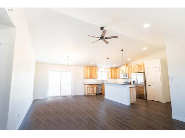 a view of a kitchen and an empty room with wooden floor