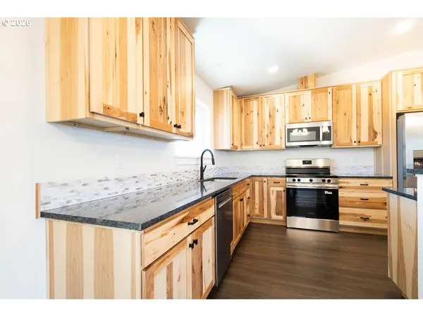 a kitchen with stainless steel appliances granite countertop a stove a sink dishwasher and a refrigerator