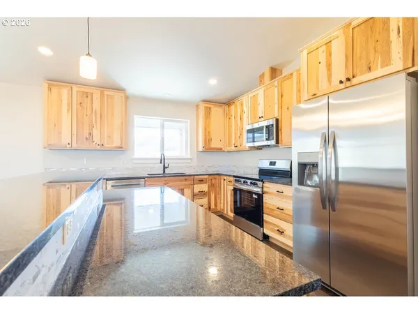 a kitchen with stainless steel appliances granite countertop a refrigerator a sink and a stove