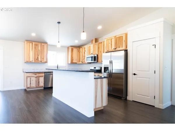 a kitchen with stainless steel appliances granite countertop a refrigerator a sink dishwasher a stove and white countertops with wooden floor