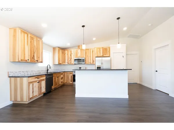 a large kitchen with granite countertop a large counter top a sink stainless steel appliances and cabinets